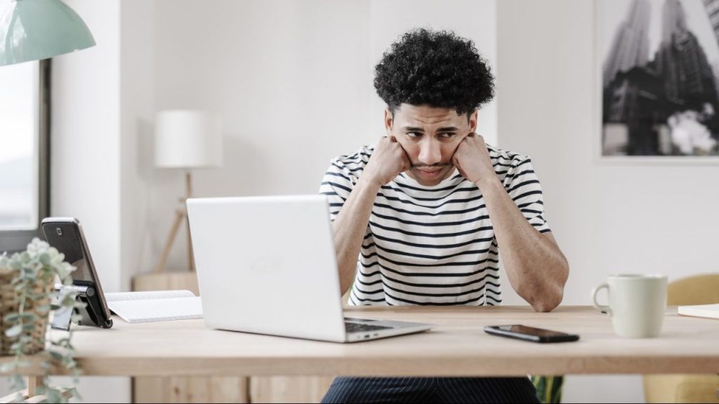 young man with laptop unhappy at work how to survive a job you hate